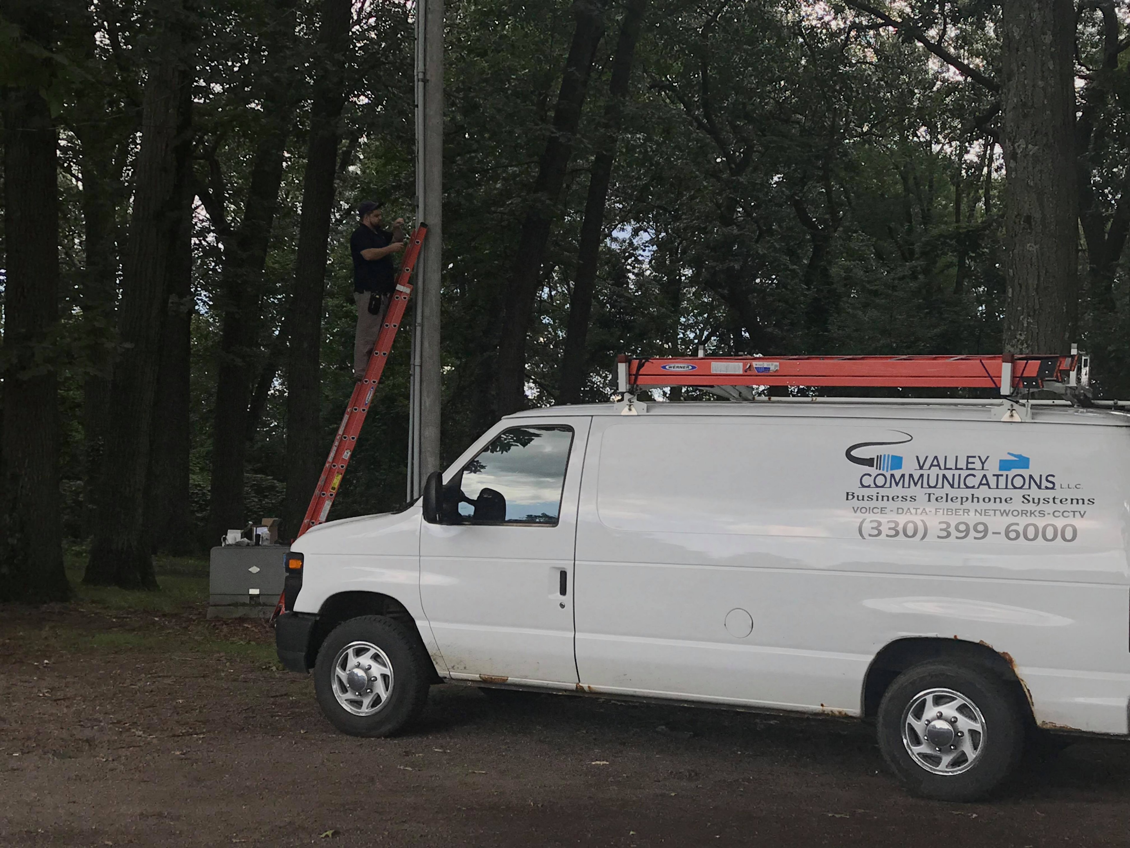 Valley Communications LLC technician on ladder performing installation